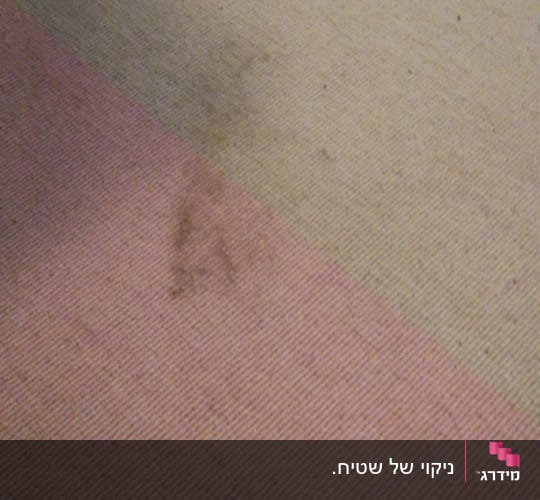 שטיח עם כתמים כהים על רקע בהיר